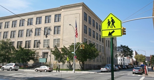 wide shot of a school zone sign near a school building