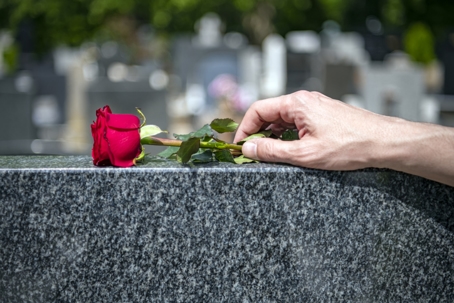 A man puts a red rose on the grave | Turner Law Group
