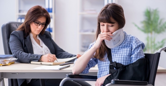 injured woman sitting in a wheelchair talking to a lawyer