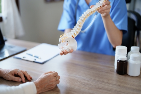 Female doctor talking patient holding spine model | Turner Law Group