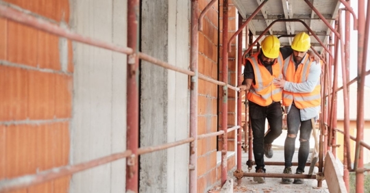a construction worker assisting his coworker walk after an injury