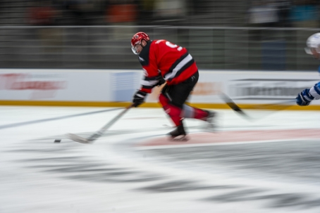 Ice hockey player in a red jersey speeding across the rink | Turner Law Group