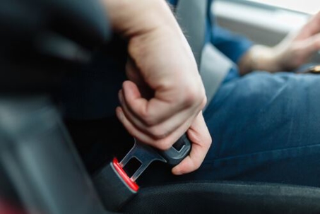 man's hand buckling seatbelt to represent roadway safety